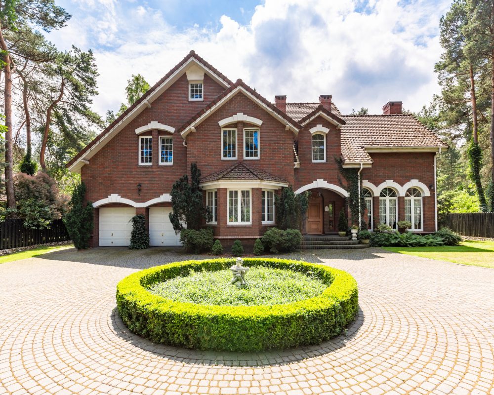 Front view of a driveway with a round garden and big, english st
